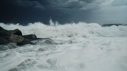 Waves splashing on shore against sky