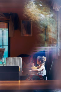 Girl eating food while sitting on table at restaurant