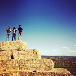 People on landscape against clear blue sky