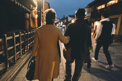Rear view of people walking on street in city