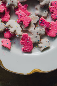 Frosted circus animal cookie pink and white sprinkled animal crackers on white plate with gold 