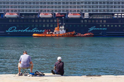 Rear view of men sitting on boat in sea