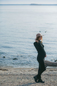 A beautiful young pregnant woman in a black turtleneck and a black tight skirt, a classic beige hat