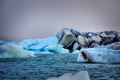 Scenic view of icebergs in water against sky