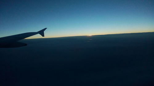 Airplane wing against sky during sunset