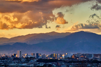 Aerial view of townscape and mountains against sky during sunset