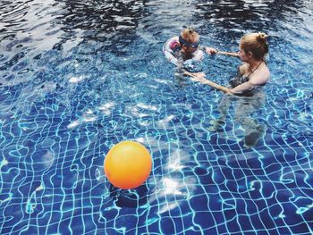 High angle view of girl with mother swimming in pool