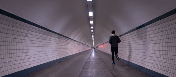 Rear view of woman walking on illuminated tunnel
