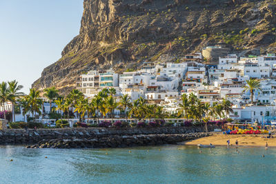 Buildings by sea against mountain