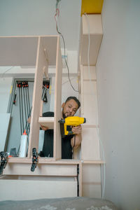 Building a wardrobe. man using framing nailer to attach wooden plywoods.