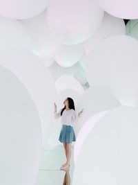 Low angle view of woman standing on balloons against wall