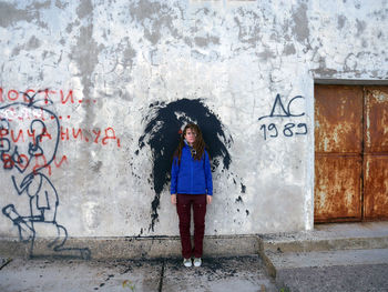 Portrait of woman standing against graffiti wall