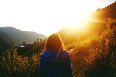 Rear view of woman standing on land against sky