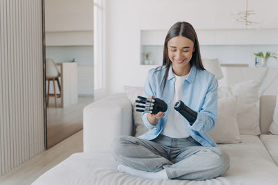 Portrait of young woman using mobile phone while sitting at home