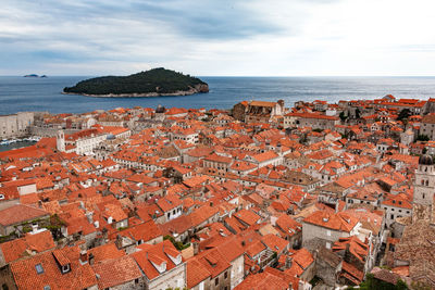 High angle view of townscape by sea against cloudy sky