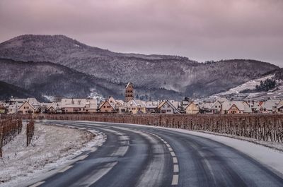 Road by mountains against sky during winter