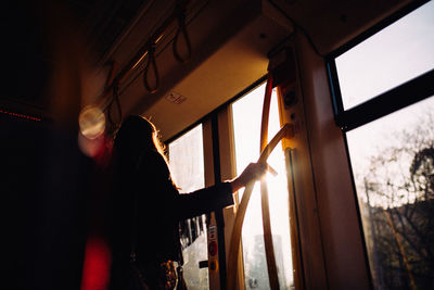 Silhouette woman standing by door in bus