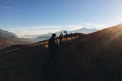 Rear view of hikers walking on mountain against sky