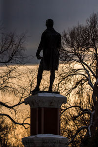 Low angle view of statue against bare tree