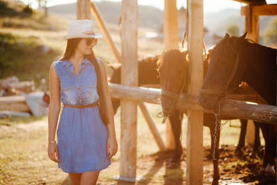 Woman looking at horses while standing by stable