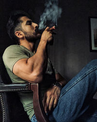 Man smoking cigar while sitting on chair