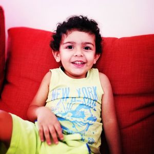 Portrait of happy little boy sitting on sofa at home