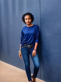 Portrait of young woman standing against wall