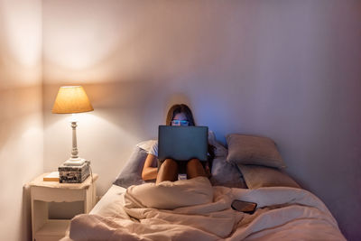 Man using laptop on bed at home