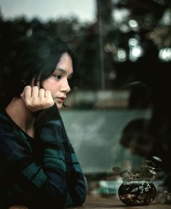 Young woman looking away while sitting at cafe