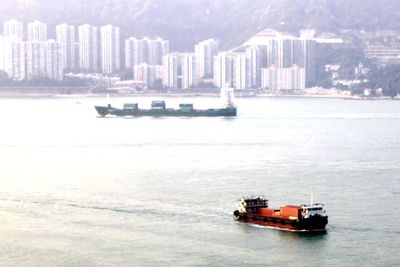 Nautical vessel on sea against cityscape