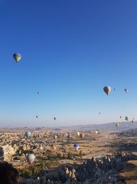 Hot air balloons flying over landscape against blue sky