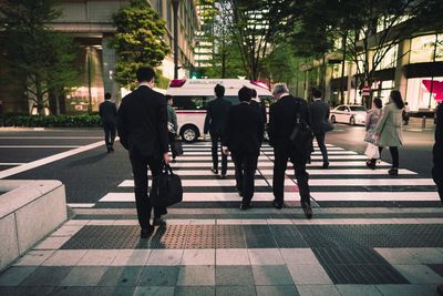 Rear view of business people crossing street in city
