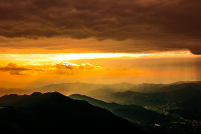 Scenic view of silhouette mountains against dramatic sky