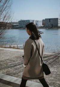 Rear view of woman standing at riverbank