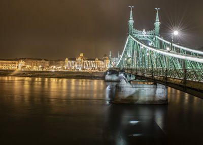 Illuminated bridge over river at night