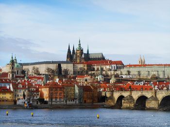 View of buildings by river against sky in city
