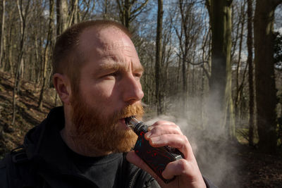 Man smoking electronic cigarette in forest