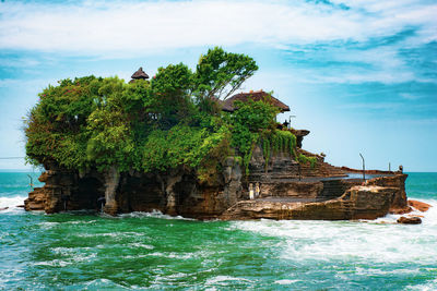 Rock formation by sea against sky