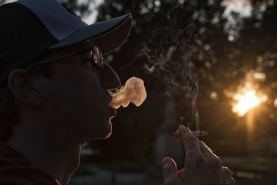 Side view of man smoking cigarette during sunset