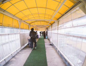 Rear view of people walking on covered bridge