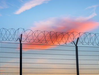 Low angle view of fence against sky during sunset