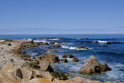 Rocks on beach against blue sky