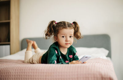 A little girl uses a phone, plays a game or watches cartoons