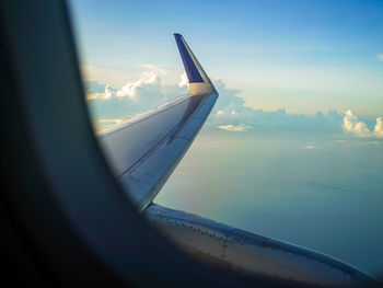 Airplane flying over glass window against sky