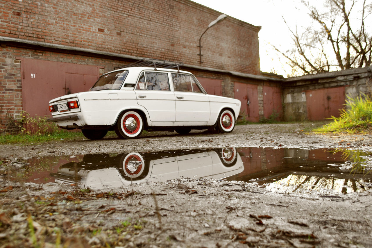 REFLECTION OF ABANDONED CAR IN PUDDLE