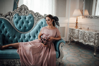 Young woman looking away while sitting on sofa at home