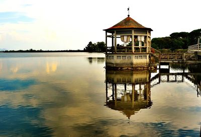 Gazebo in lake by building against sky
