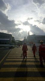 Men moving on road against cloudy sky