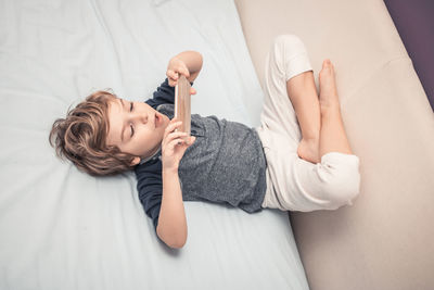 High angle view of cute boy lying on sofa at home