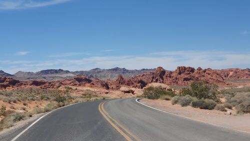 Road leading towards mountains against sky